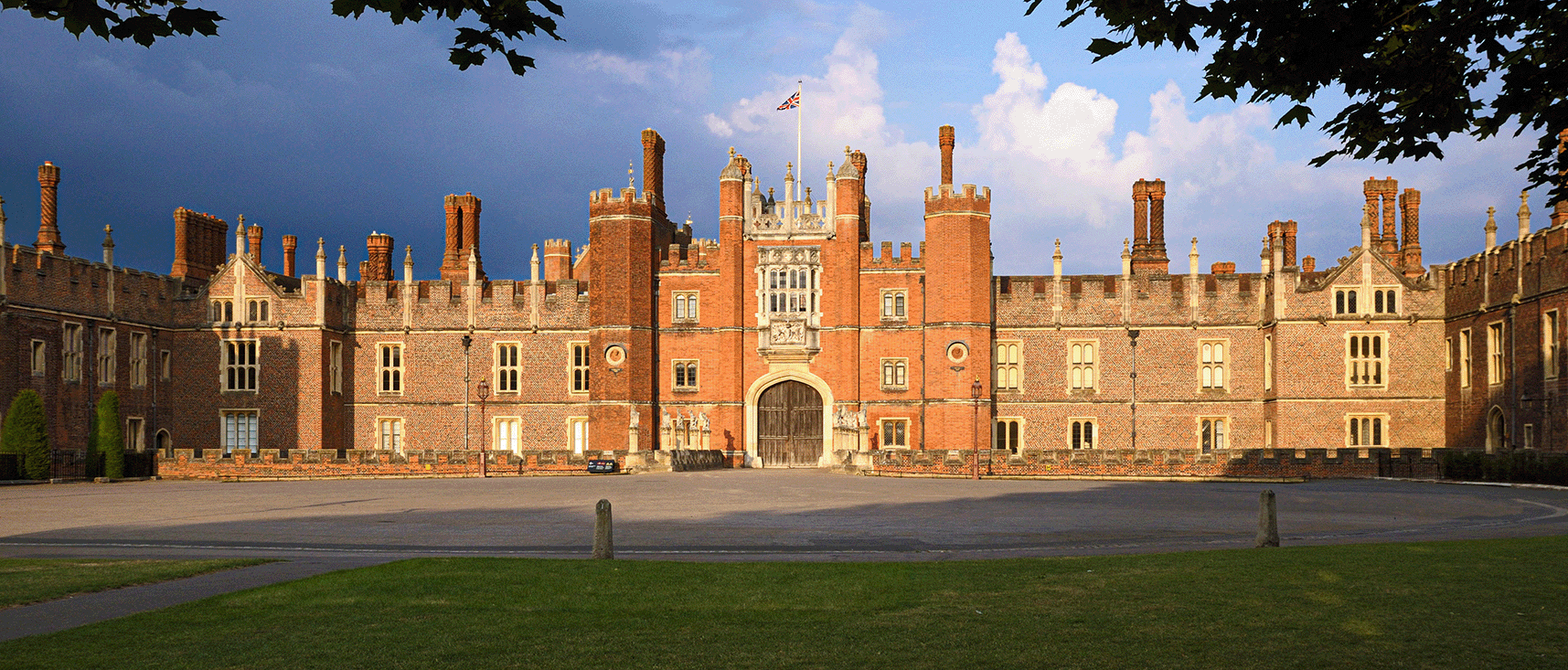 Photograph of the front façade of a large red brick palace with many crenelated chimneys.